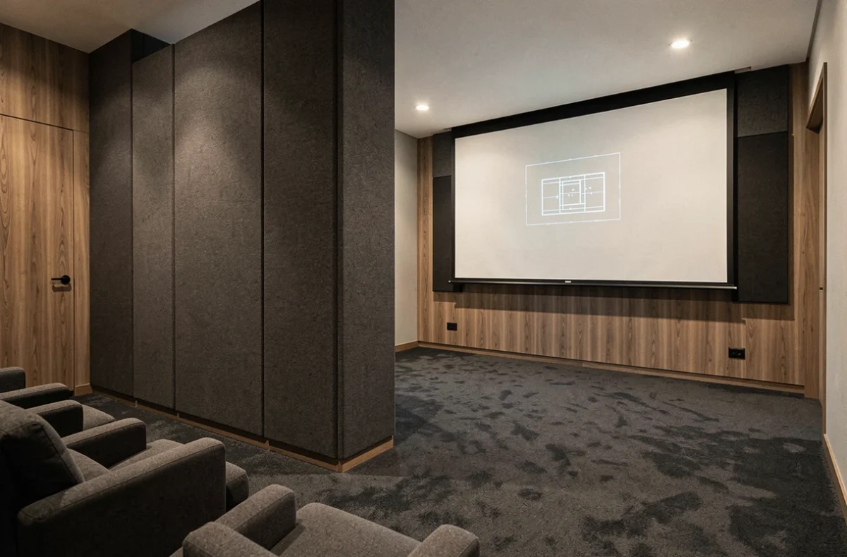 Cloison demi-hauteur en tissu acoustique dans une salle de home cinéma moderne avec sièges rembourrés et écran de projection